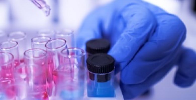 Scientist wearing PPE pipettes chemical solutions into test tubes