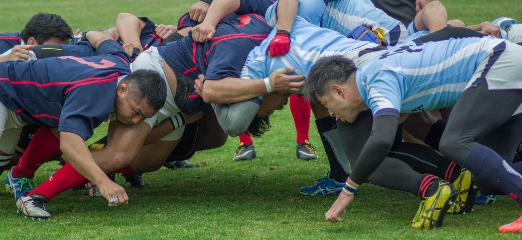 a group of rugby players on the pitch, in a scrum formation